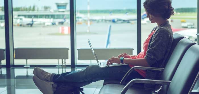 mujer nómada digital con su laptop en aeropuerto