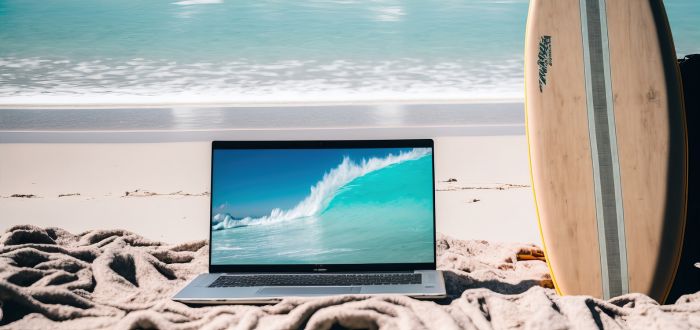 Laptop en la playa con tabla de surf | Nomadismo digital